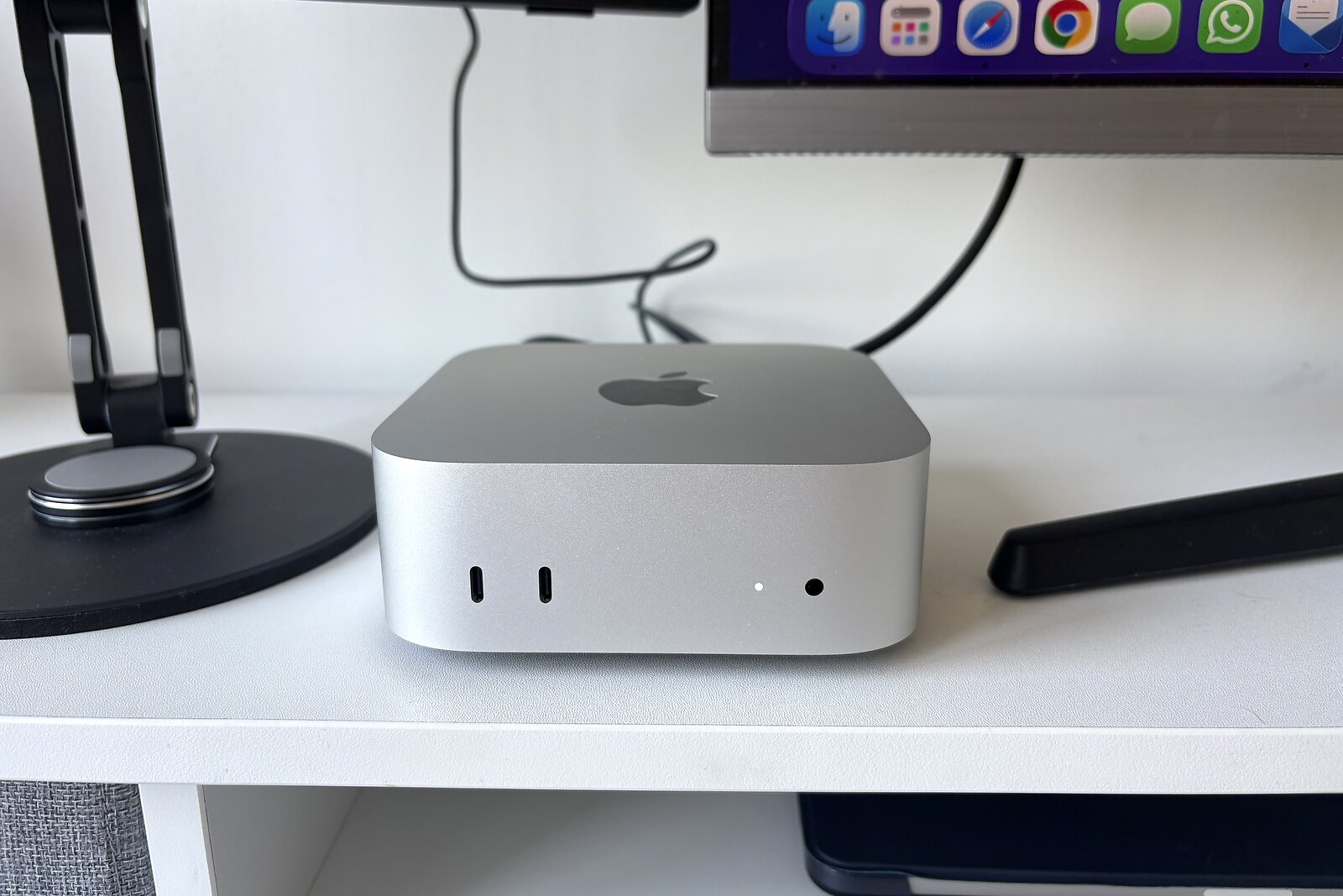 The M4 Pro Mac mini sat on a monitor shelf between two displays